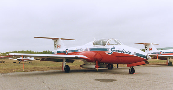 Tutor serial 114145 as Snowbird 6, is seen on the damp tarmac at overcast Mont Laurier airport, Quebec. Snowbird 5, seen off to the right, is Tutor 114081. (Bill Upton Photo)